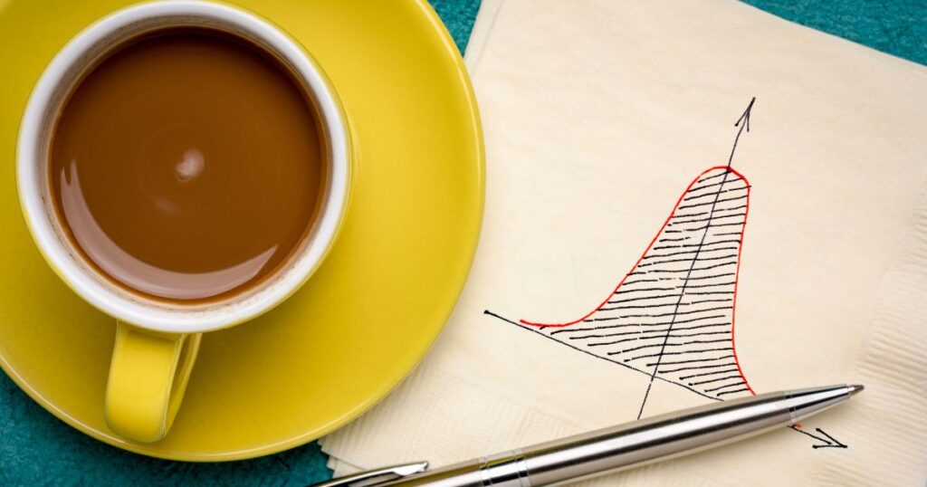 A bell curve sketch on a napkin near a cup of espresso