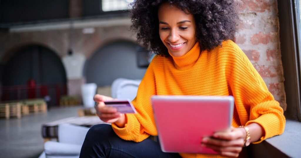 Woman shops online holding an iPad and credit card