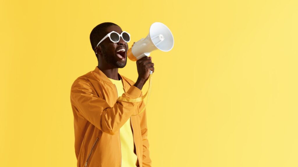 Men speaking into a megaphone over a yellow background